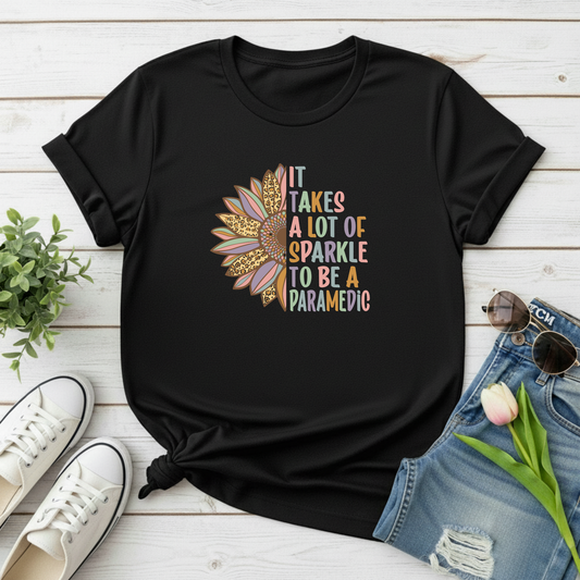 Black t-shirt with colorful sunflower design and text on a wooden surface with shoes and shorts.