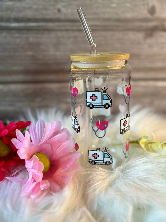Clear tumbler with ambulance and heart stethoscope on a wooden surface with flowers.