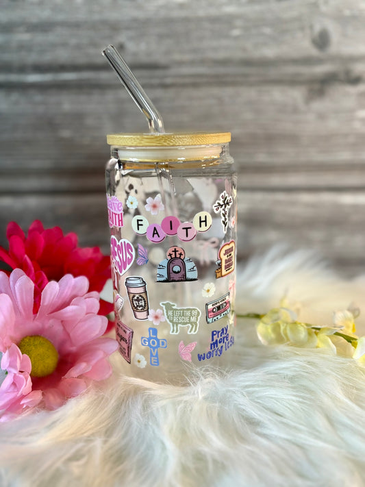 Glass tumbler with colorful stickers on a wooden surface with flowers and lights.
